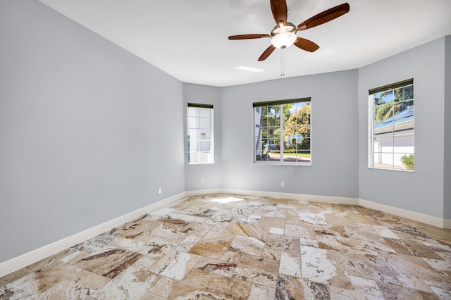 spare room featuring stone finish floor, ceiling fan, and baseboards