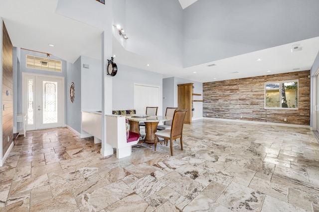 dining area with a towering ceiling, stone tile floors, baseboards, and recessed lighting