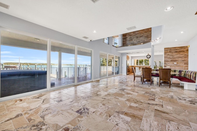 interior space with baseboards, a high ceiling, visible vents, and stone tile flooring