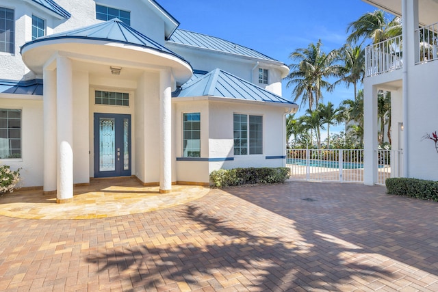 property entrance featuring metal roof, a standing seam roof, fence, and stucco siding