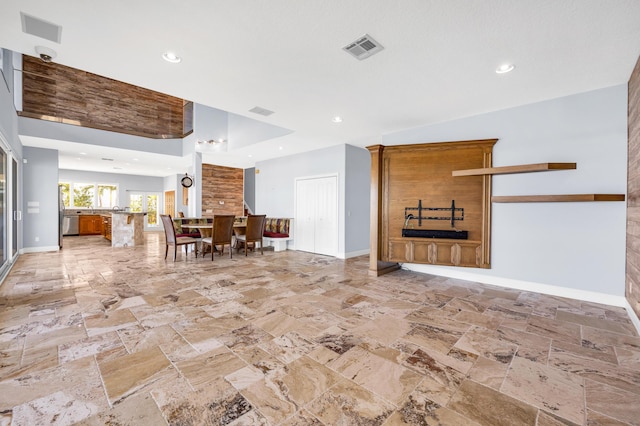 unfurnished living room with recessed lighting, stone finish floor, visible vents, and baseboards