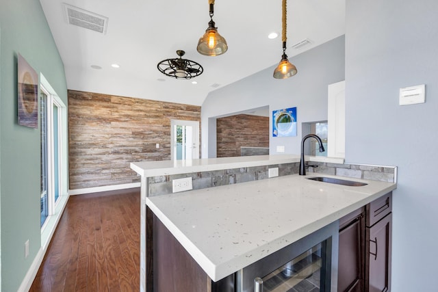 kitchen with wooden walls, beverage cooler, an accent wall, a sink, and visible vents