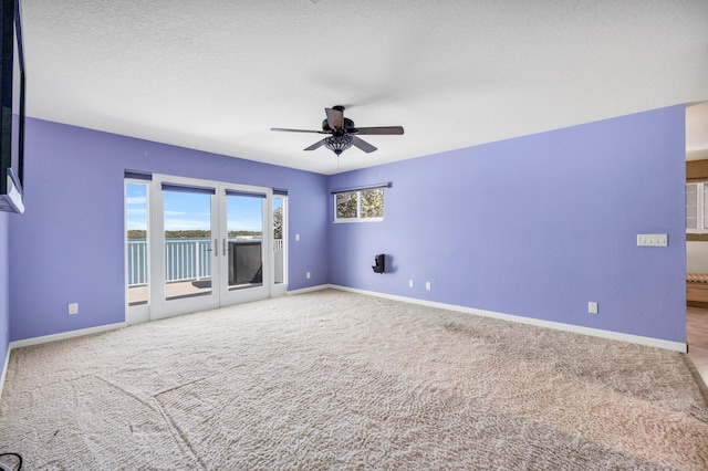 carpeted spare room with ceiling fan, a textured ceiling, and baseboards