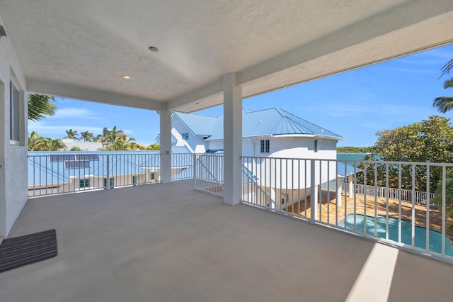 view of patio / terrace with a balcony, a water view, and fence