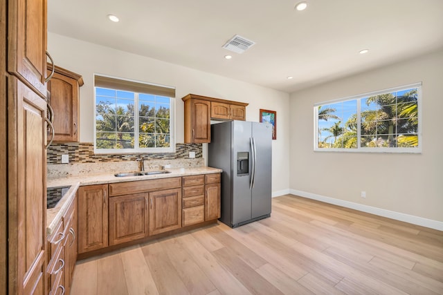 kitchen featuring a healthy amount of sunlight, stainless steel fridge, visible vents, and a sink