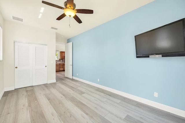 unfurnished bedroom with light wood-type flooring, baseboards, visible vents, and a closet