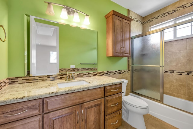 full bath with toilet, shower / bath combination with glass door, tile patterned flooring, vanity, and tile walls