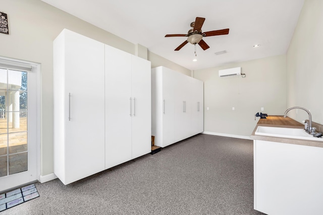 interior space with ceiling fan, speckled floor, a sink, baseboards, and an AC wall unit