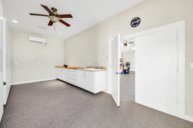 interior space featuring a wall unit AC, ceiling fan, baseboards, and a sink