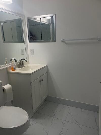 bathroom featuring marble finish floor, toilet, vanity, and baseboards