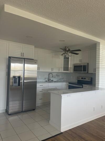 kitchen featuring a sink, stainless steel appliances, light countertops, white cabinetry, and backsplash