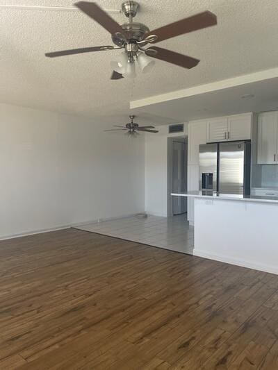 unfurnished living room with a textured ceiling, a ceiling fan, and dark wood-style flooring