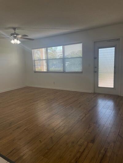 spare room with baseboards, dark wood-style flooring, and ceiling fan