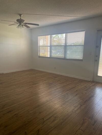 spare room featuring baseboards, a textured ceiling, ceiling fan, and dark wood-style flooring