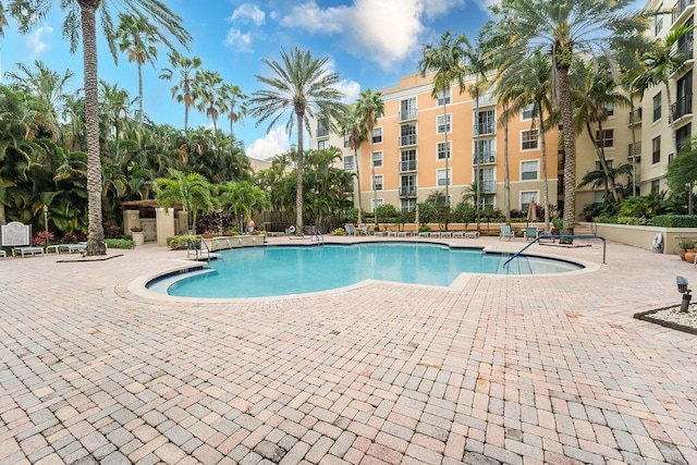 community pool with a patio area and fence