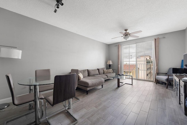 living room with a textured ceiling, wood finished floors, a ceiling fan, and baseboards