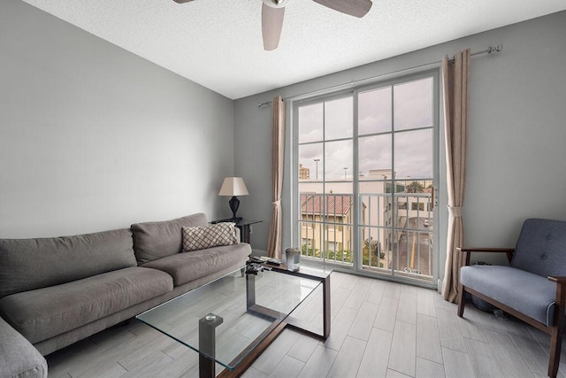 living room featuring a textured ceiling, a ceiling fan, and wood finish floors