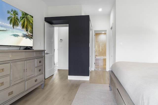 bedroom featuring light wood-style floors, connected bathroom, and baseboards