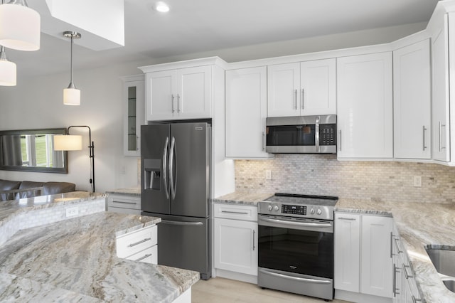 kitchen featuring tasteful backsplash, white cabinets, glass insert cabinets, hanging light fixtures, and stainless steel appliances