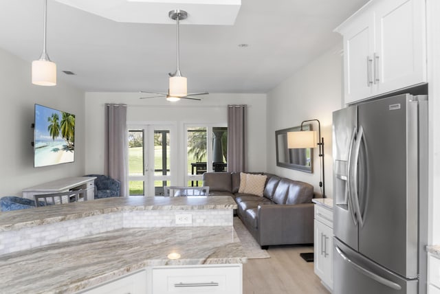 kitchen featuring light wood-style floors, open floor plan, white cabinets, light stone countertops, and stainless steel fridge with ice dispenser