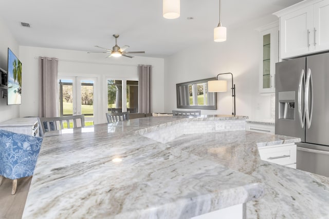 kitchen with visible vents, white cabinets, glass insert cabinets, light stone countertops, and stainless steel refrigerator with ice dispenser