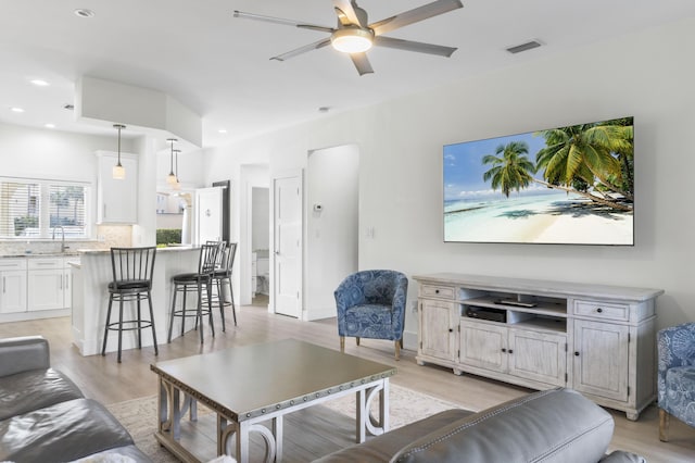 living area featuring light wood-style floors, ceiling fan, visible vents, and recessed lighting