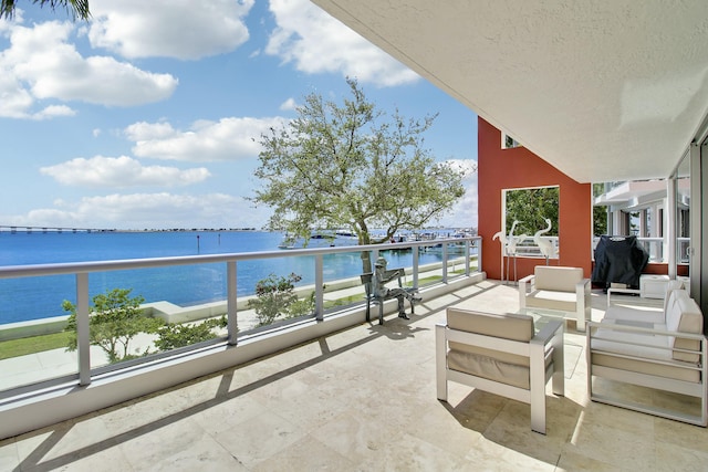 balcony with area for grilling, outdoor lounge area, and a water view