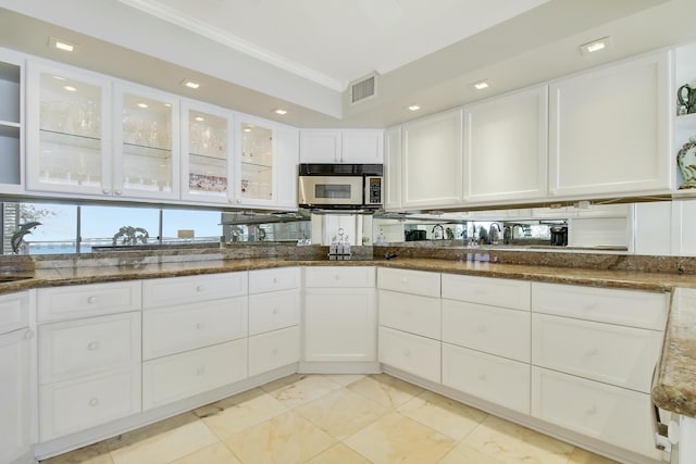 kitchen featuring stainless steel microwave, crown molding, visible vents, and white cabinetry