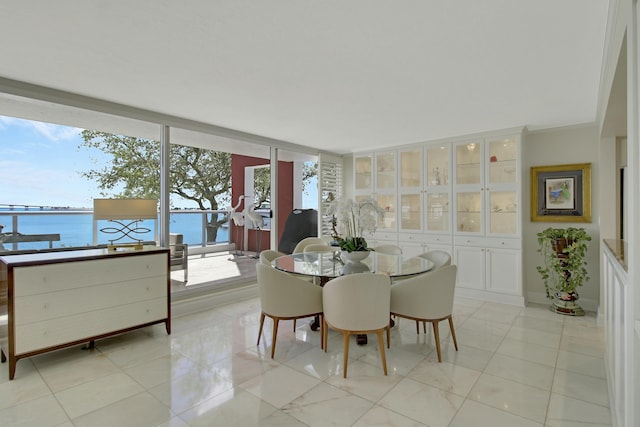 dining room featuring a wall of windows, a water view, and light tile patterned flooring