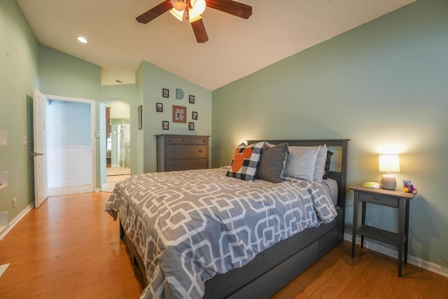 bedroom featuring baseboards, arched walkways, ceiling fan, wood finished floors, and vaulted ceiling