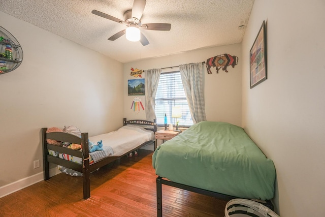 bedroom featuring baseboards, a textured ceiling, a ceiling fan, and wood finished floors