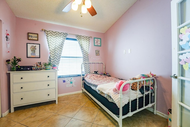 bedroom with light tile patterned floors, baseboards, ceiling fan, vaulted ceiling, and a textured ceiling