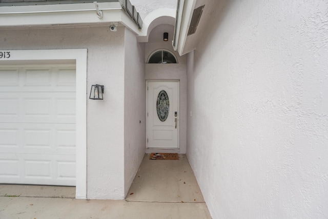 doorway to property with a garage and stucco siding