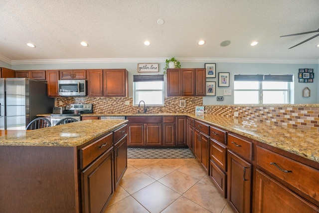 kitchen with light tile patterned floors, ornamental molding, light stone countertops, stainless steel appliances, and backsplash