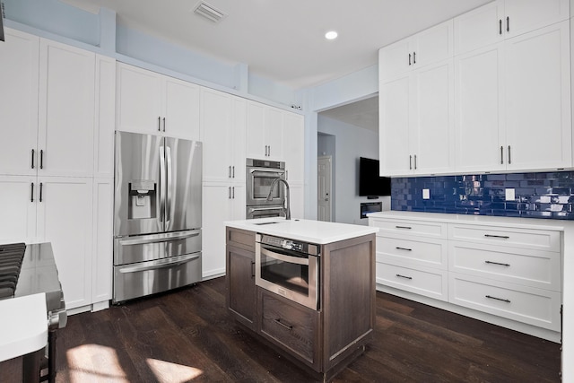 kitchen featuring visible vents, light countertops, tasteful backsplash, stainless steel fridge, and dark wood finished floors