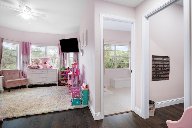 recreation room with a ceiling fan, baseboards, and dark wood-style flooring