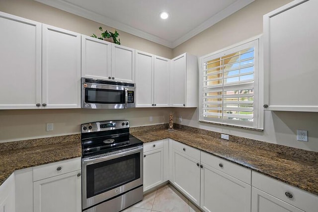 kitchen with appliances with stainless steel finishes, white cabinetry, crown molding, and dark stone countertops