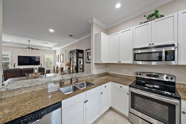 kitchen featuring a sink, white cabinets, appliances with stainless steel finishes, dark stone counters, and a raised ceiling