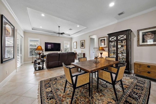 dining space featuring ornamental molding, a raised ceiling, light tile patterned flooring, and baseboards