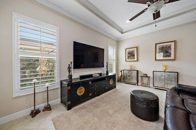 living area featuring ceiling fan, a tray ceiling, ornamental molding, and baseboards