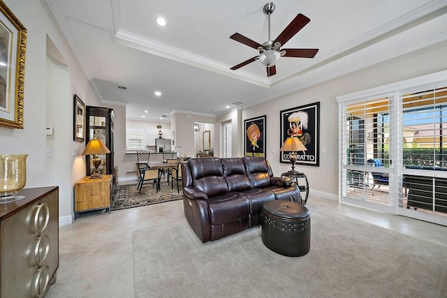 living room featuring recessed lighting, a tray ceiling, and ornamental molding