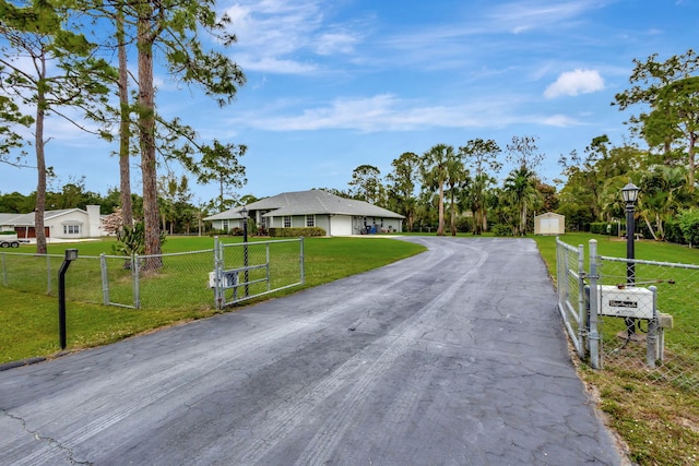 view of road with driveway, street lighting, a gate, and a gated entry