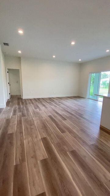 unfurnished room with wood finished floors, visible vents, and baseboards