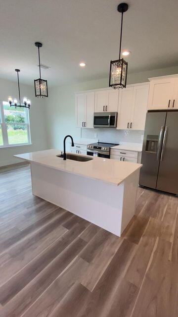 kitchen with stainless steel appliances, light countertops, white cabinets, and a sink