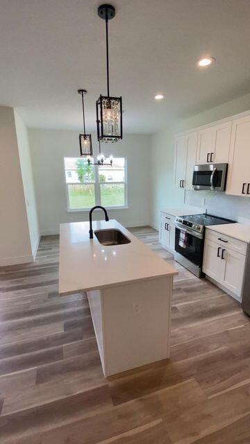 kitchen with appliances with stainless steel finishes, light wood-style flooring, a sink, and white cabinetry