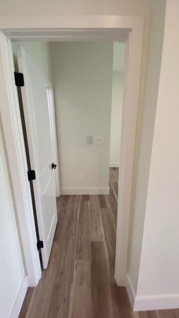 corridor with wood finished floors and baseboards