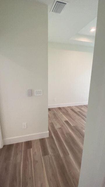 empty room with visible vents, baseboards, and wood finished floors