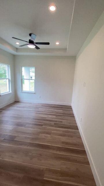 unfurnished room featuring baseboards, a raised ceiling, and wood finished floors