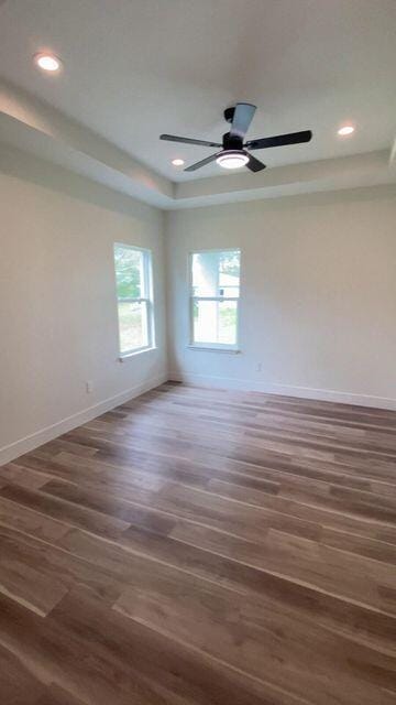 unfurnished room with baseboards, dark wood finished floors, a tray ceiling, and recessed lighting