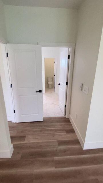 hall with baseboards and wood finished floors